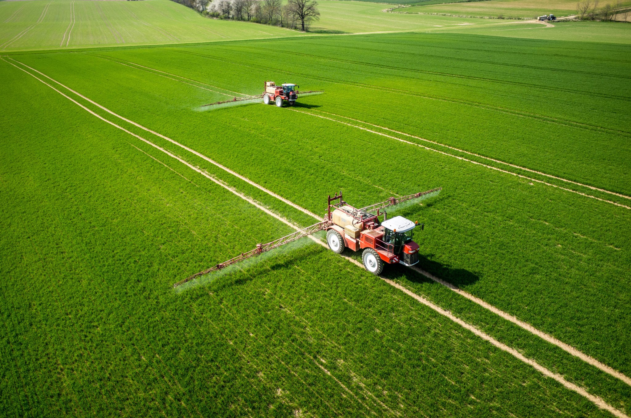 Aerial view of the tractor Aerial view of the tractor spraying the chemicals on the large green field